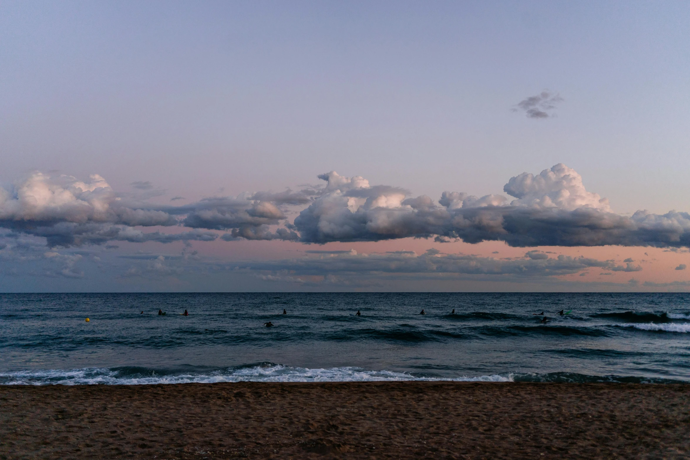 a group of people riding surfboards on top of a sandy beach, by Carey Morris, unsplash contest winner, australian tonalism, panorama view of the sky, cotton candy clouds, calm evening, mediterranean