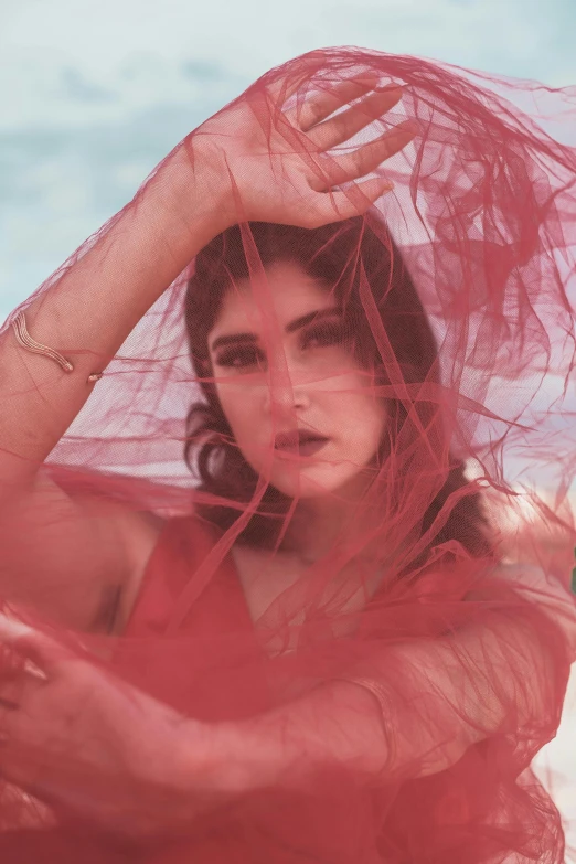 a woman in a red dress with a veil over her head, an album cover, trending on pexels, salma hayek, iridescent ethereal veils, alexandra daddario, summertime