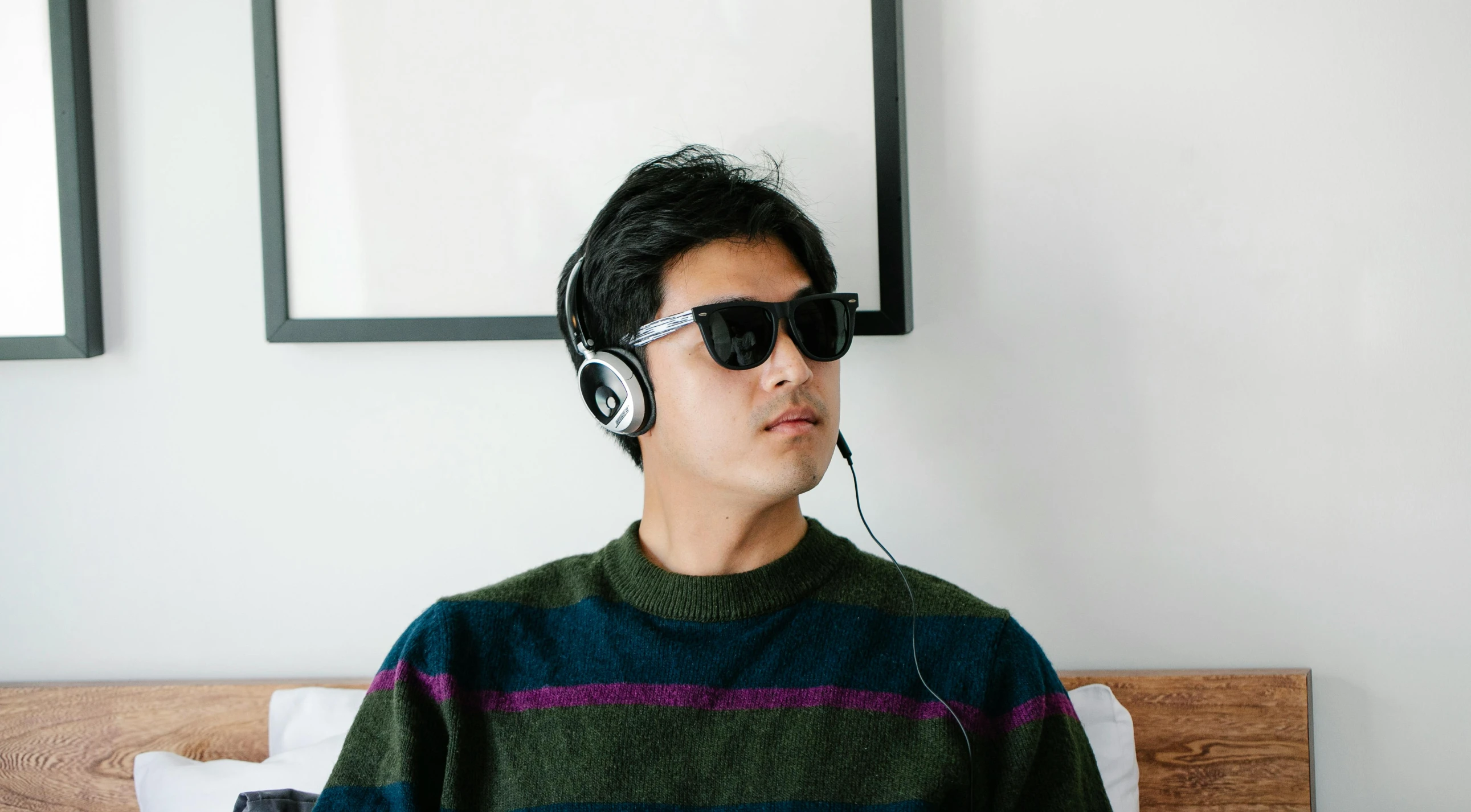 a man sitting on top of a bed wearing headphones, inspired by Zhu Da, trending on pexels, hyperrealism, wear ray - ban glass, multi-dimensional, multi chromatic, casually dressed