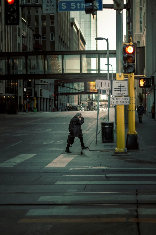 a man walking across a street next to a traffic light, by Andrew Domachowski, minneapolis, downtown, sweeping, photo taken in 2 0 2 0