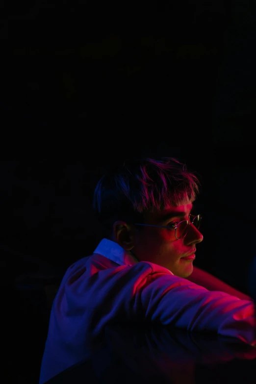 a man holding a tennis racquet in a dark room, an album cover, pexels contest winner, looking off to the side, barely lit warm violet red light, joel fletcher, man sitting facing away