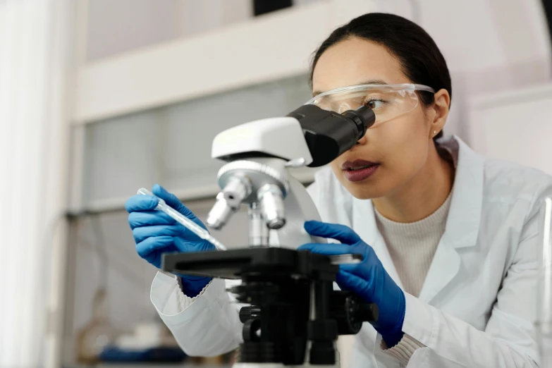 a woman in a lab coat looking through a microscope, a microscopic photo, shutterstock, fan favorite, asian origin, australian, instagram photo