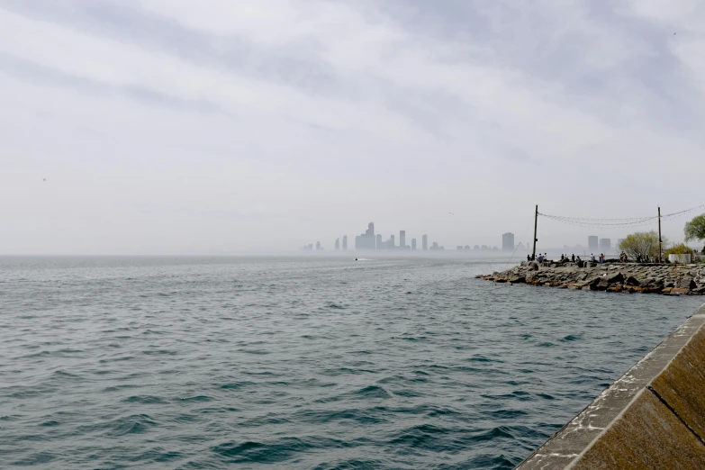 a large body of water with a city in the background, unsplash, hurufiyya, foggy day outside, near a jetty, karachi skyline background, 2 0 2 2 photo