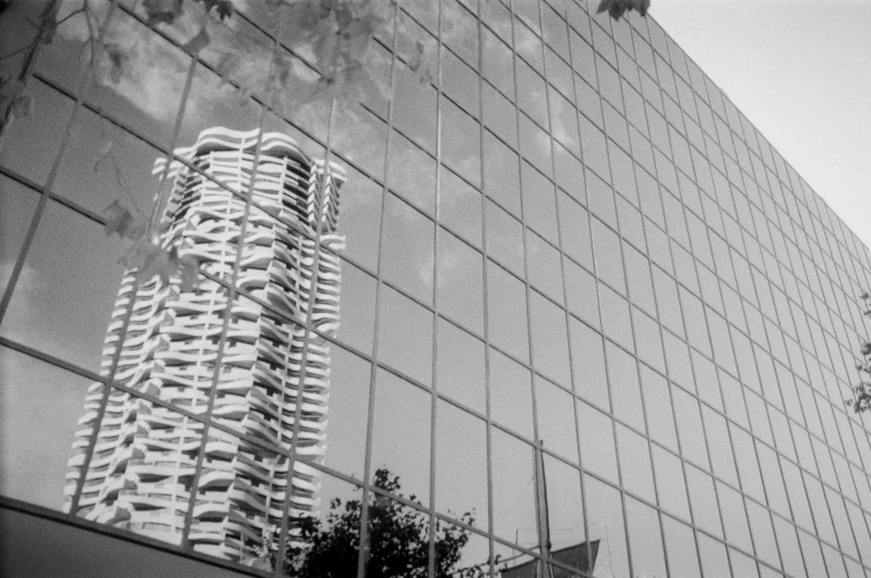 a black and white photo of a tall building, inspired by André Kertész, pexels contest winner, surrealism, mirror and glass surfaces, video still, bangkok, rippling reflections