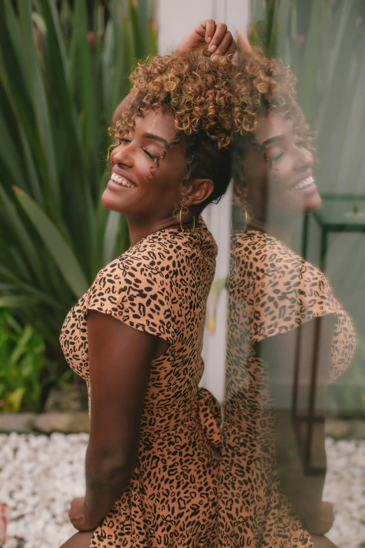 a woman in a leopard print dress posing for a picture, a picture, by Daniel Seghers, trending on pexels, happening, admiring her own reflection, afro hair, turning her head and smiling, focus her back