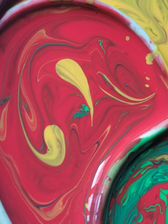 a bowl of paint sitting on top of a table, inspired by James Rosenquist, abstract expressionism, close - up photograph, red swirls, green magenta and gold, raspberry banana color