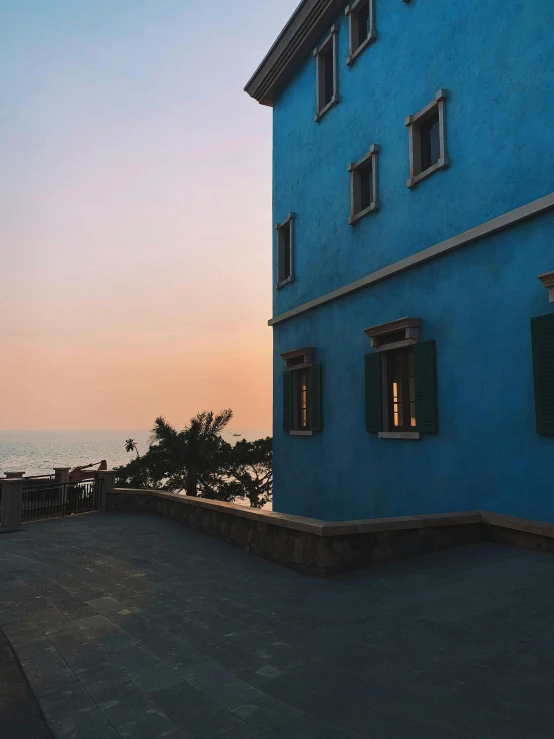 a blue building next to the ocean at sunset, profile image, conde nast traveler photo, window view, instagram photo