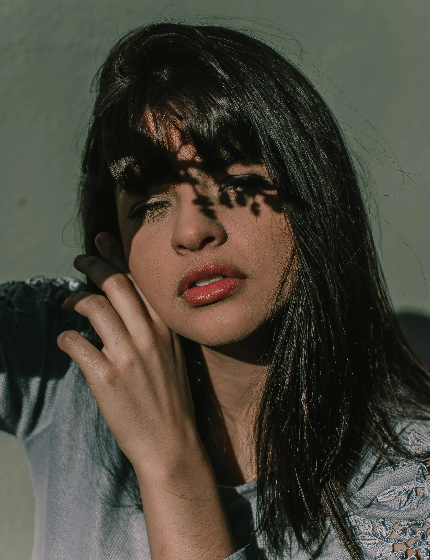 a woman holding a cell phone to her ear, an album cover, inspired by Elsa Bleda, trending on pexels, long dark hair with bangs, non binary model, portrait of ((mischievous)), female image in shadow