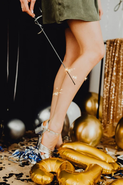 a woman standing next to a bunch of balloons, a tattoo, trending on pexels, holography, shows a leg, silver with gold accents, new years eve, pins of light