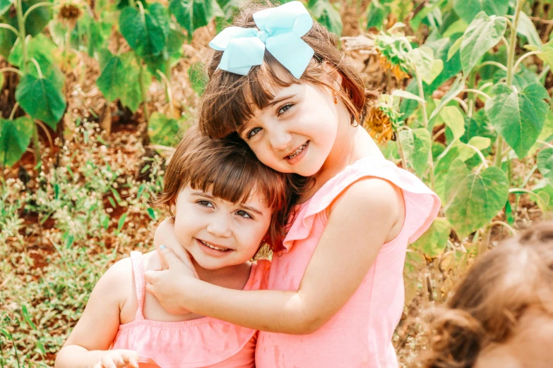 two little girls hugging each other in a field, pexels contest winner, wearing a pink head band, avatar image, brunettes, with ivy