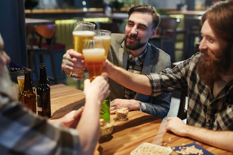 a group of men sitting at a table drinking beer, a photo, shutterstock, fan favorite, serving suggestion, half image, rectangle