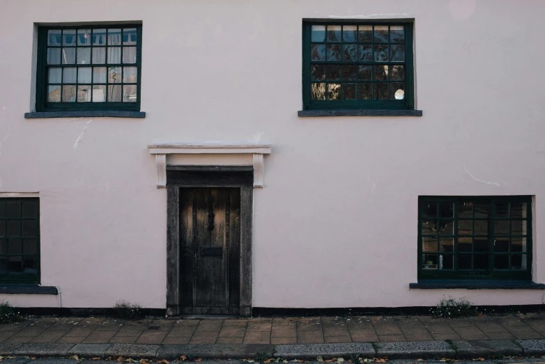 a red fire hydrant sitting in front of a pink building, an album cover, inspired by Rachel Whiteread, unsplash, arts and crafts movement, black windows, timbered house with bricks, about to enter doorframe, 1 8 th century style