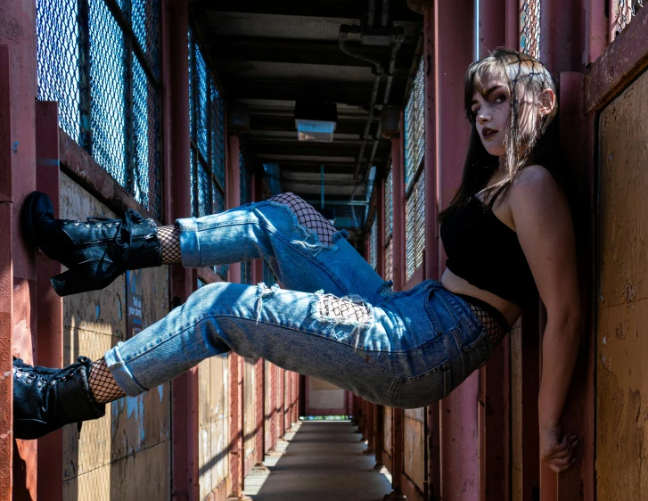 a woman leaning against a wall with her legs in the air, a portrait, inspired by Elsa Bleda, pexels contest winner, graffiti, cyberpunk 2 0 y. o model girl, blue jeans, on a bridge, stood in a cell