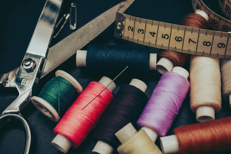 a bunch of spools of thread next to a pair of scissors, trending on pexels, leather clothing, 9 9 designs, thumbnail, embroidered robes