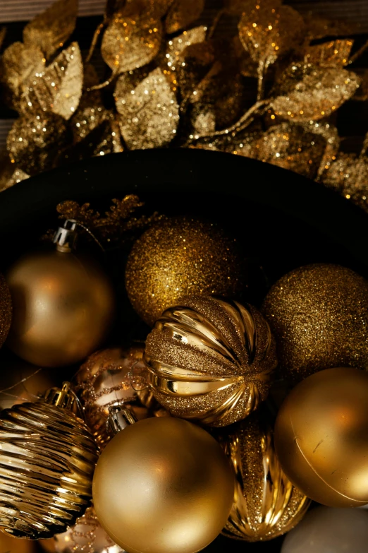 a bowl filled with gold ornaments on top of a table, dark vignette, holiday vibe, award - winning, close up details