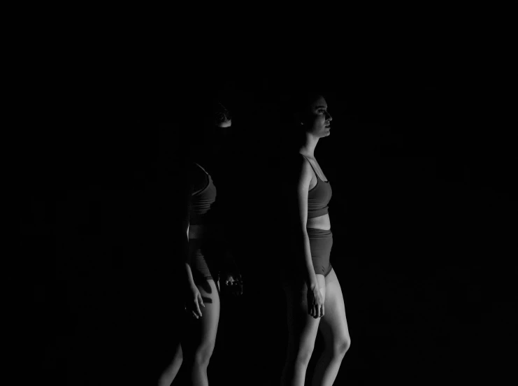 a couple of women standing next to each other, a black and white photo, by Emma Andijewska, unsplash, conceptual art, 8 k. volumetric lighting. dark, athlete photography, animation, recital