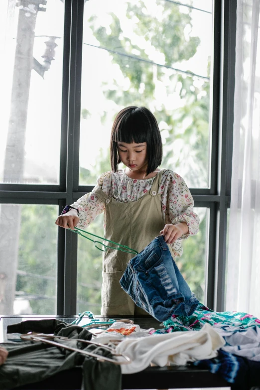 a woman ironing clothes on a bed in front of a window, inspired by Ni Yuanlu, pexels contest winner, process art, wearing blue jean overalls, little girl, inspect in inventory image, pulling strings