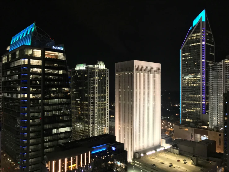 a view of a city at night from the top of a building, three towers, pittsburg, tyndall rays, glass buildings