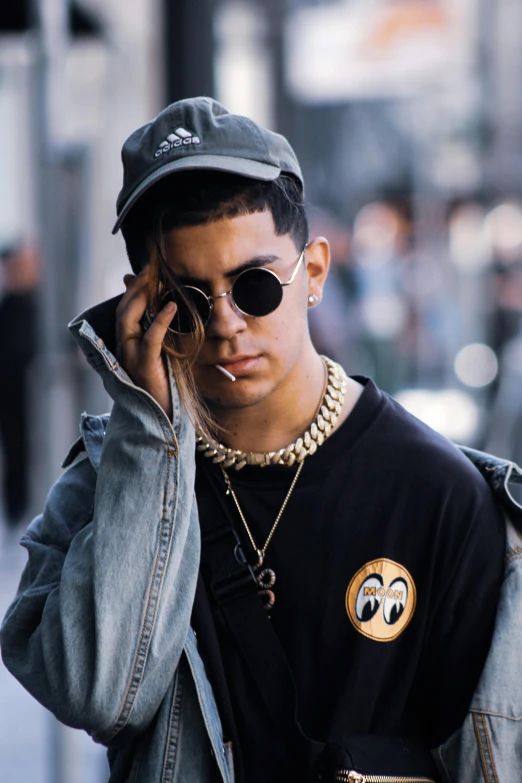 a man walking down a street talking on a cell phone, an album cover, inspired by Carlos Berlanga, trending on pexels, realism, wearing sunglasses and a cap, non binary model, rapper jewelry, yzy gap