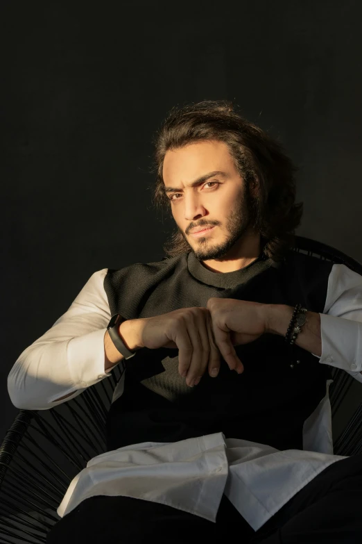 a man with long hair sitting in a chair, an album cover, inspired by Nabil Kanso, trending on pexels, romanticism, acting headshot, indian super model, raden saleh, casually dressed