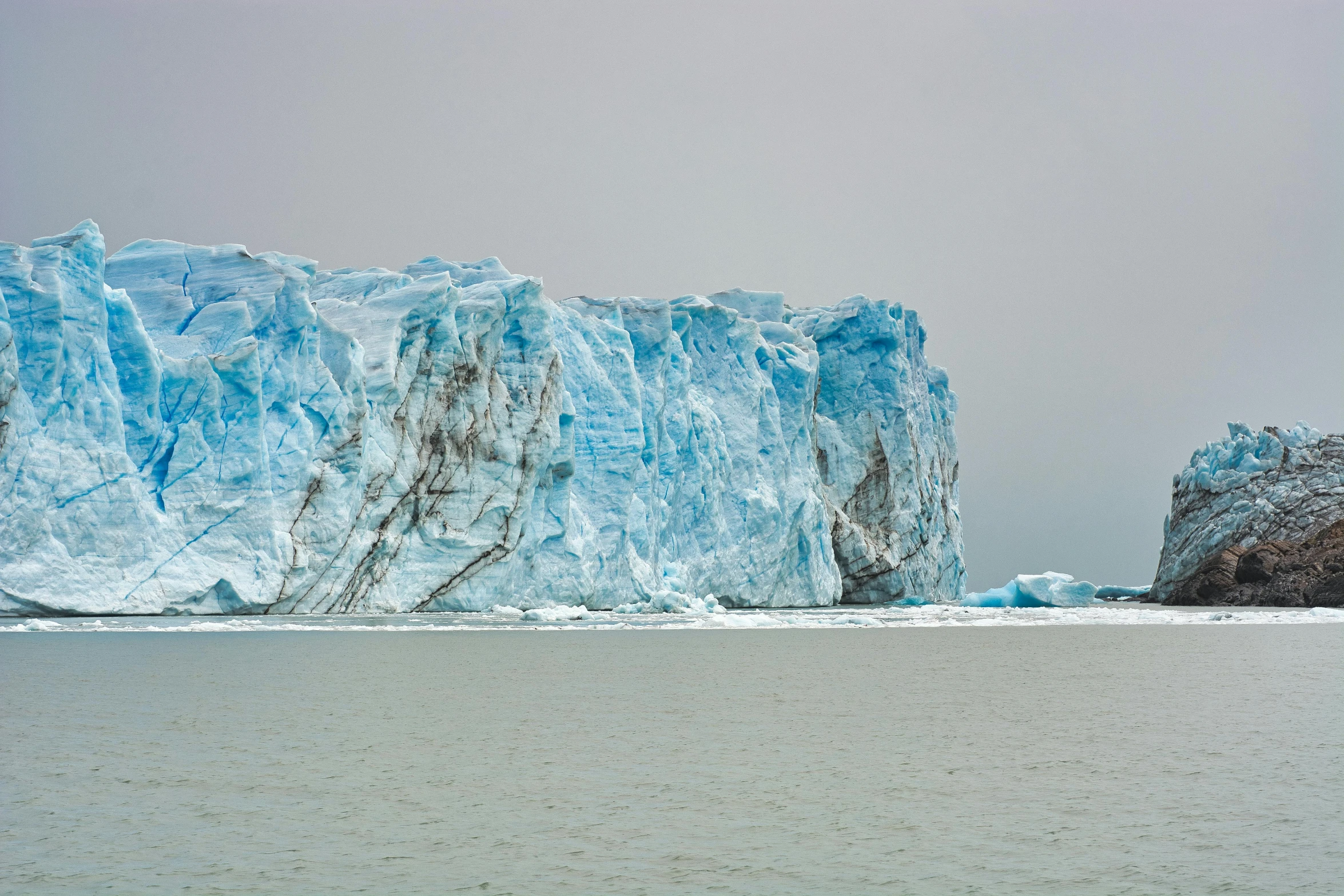 a large iceberg in the middle of a body of water, by Alison Geissler, pexels contest winner, hyperrealism, wall of water either side, muted cold colors, 2 0 2 2 photo, patagonian