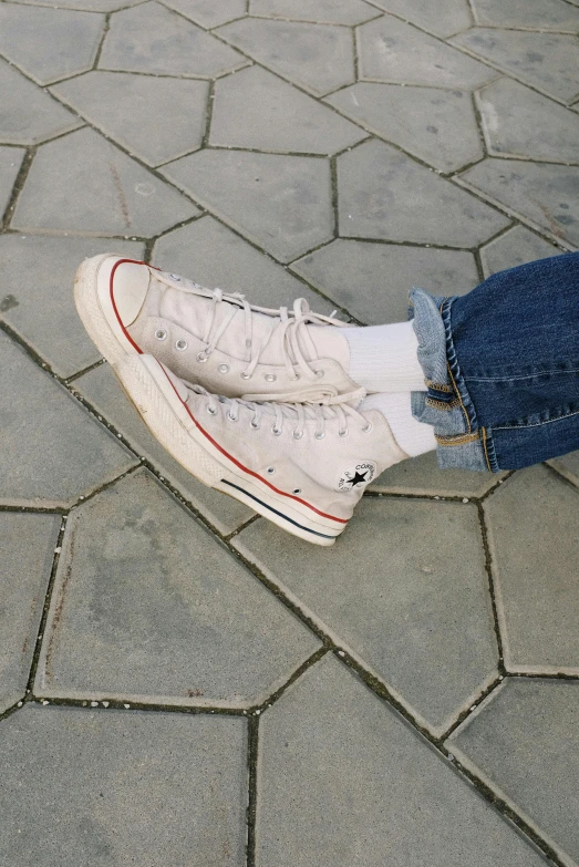 a person sitting on the ground with their feet on a skateboard, a picture, inspired by Elsa Bleda, trending on pexels, sots art, wearing red converse shoes, pale sober colors 9 0 %, wearing jeans, layered detailed