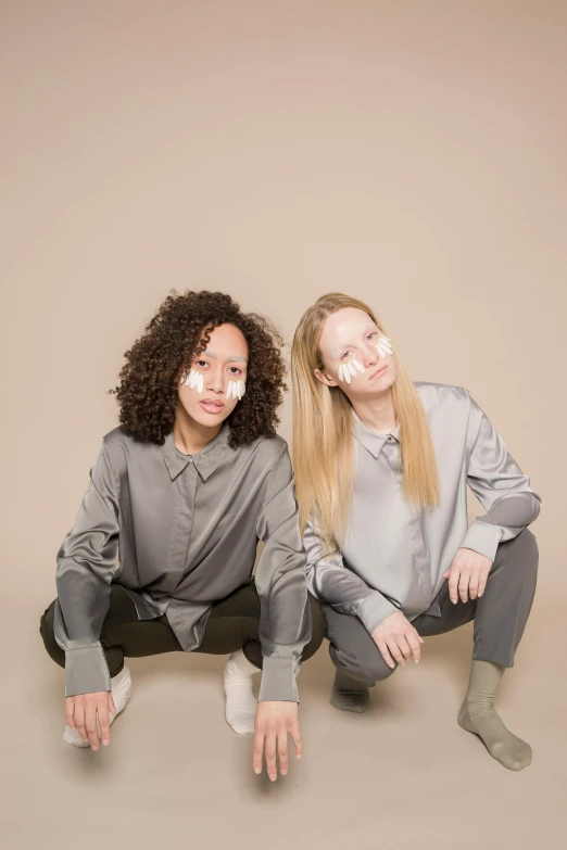 a couple of women sitting next to each other, an album cover, inspired by Wang Duo, antipodeans, wear's beige shirt, bowater charlie and brom gerald, grey and silver, twins