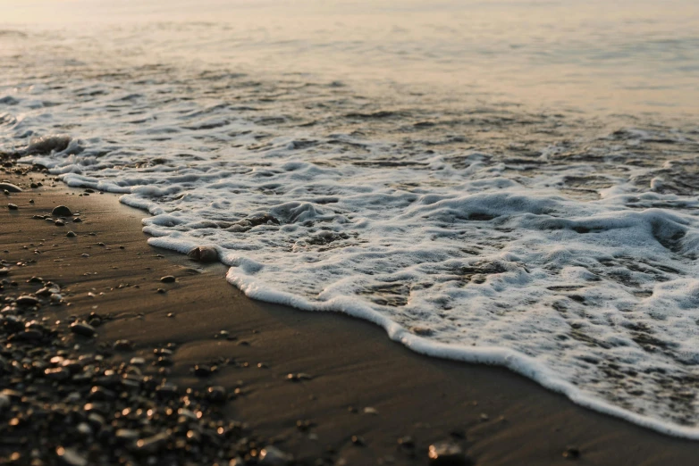 a body of water sitting on top of a sandy beach, pexels contest winner, foamy waves, early evening, thumbnail, black sea