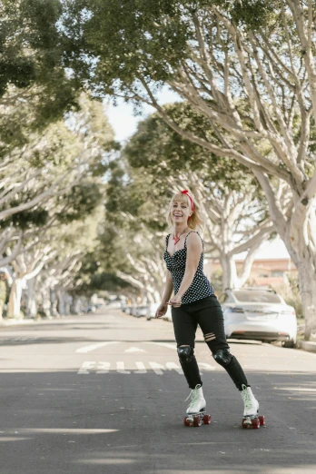 a woman riding a skateboard down a street, inspired by Sydney Carline, next to a tree, rockabilly, sydney sweeney, southern california