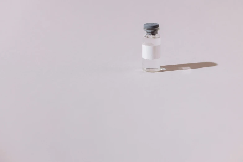 a small bottle sitting on top of a white table, postminimalism, iv pole, smol, biotech, grey