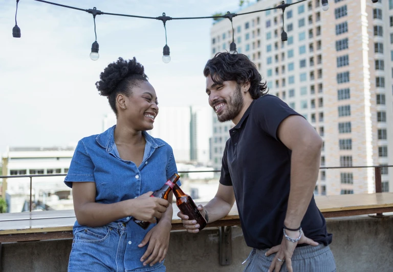 a man and a woman standing next to each other, pexels contest winner, happening, drinking beer and laughing, rooftop, beautiful city black woman only, hispanic