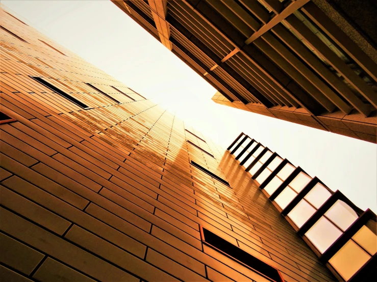 a tall brick building with windows and a sky background, inspired by Ricardo Bofill, unsplash, modernism, golden glow, iron cladding, thumbnail, a wooden