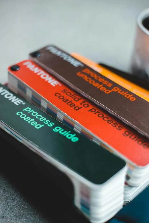 a stack of credit cards next to a cup of coffee, unsplash, process art, pantone color, orange safety labels, color chart, resin coated