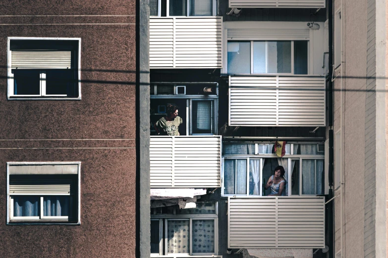 a couple of people that are looking out of a window, by Yasushi Sugiyama, unsplash, brutalism, stacked houses, single flat colour, ten flats, elaborate latticed balconies