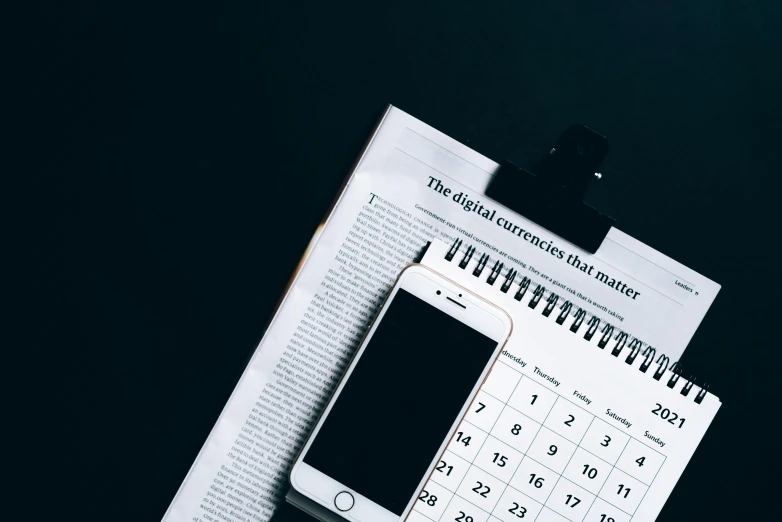 a cell phone sitting on top of a desk next to a calendar, by Carey Morris, trending on unsplash, dark and white, knolling, cover shot, performing