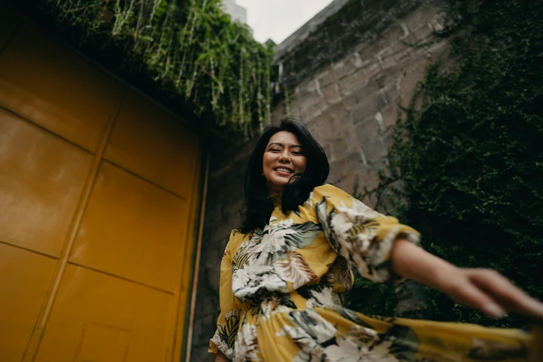 a woman standing in front of a yellow door, pexels contest winner, happening, batik, playful smile, avatar image, windy mood