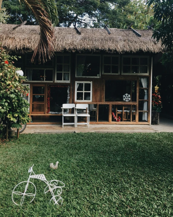 a white bicycle sitting on top of a lush green field, unsplash, sumatraism, luxurious wooden cottage, snapchat photo, palm trees outside the windows, 👰 🏇 ❌ 🍃