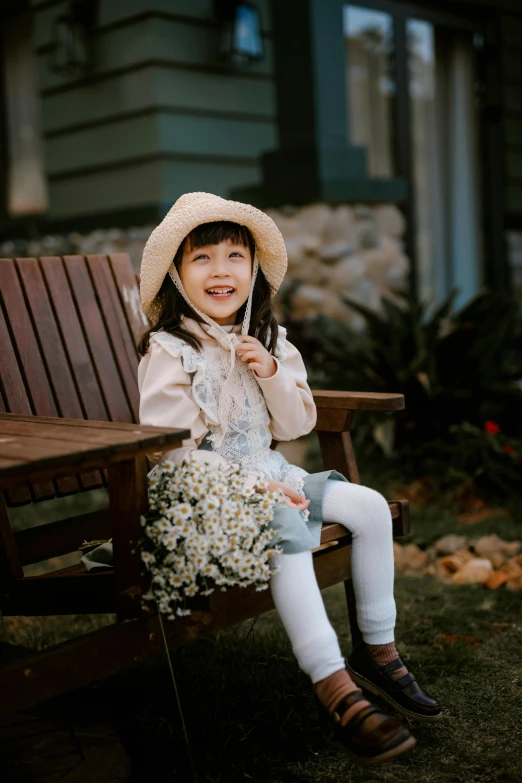 a little girl sitting on top of a wooden bench, dang my linh, warm and gentle smile, in a comfortable chair, 15081959 21121991 01012000 4k