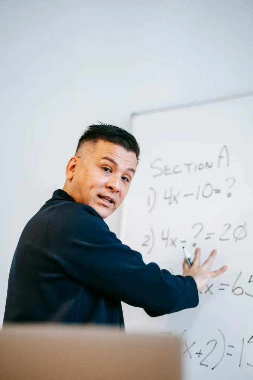 a man standing in front of a whiteboard with writing on it, by Robbie Trevino, academy headmaster, darren quach, a high angle shot, maths