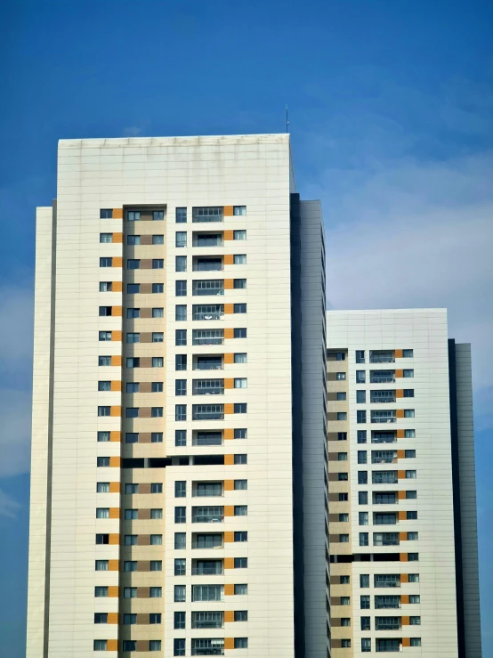 a couple of tall buildings sitting next to each other, inspired by Ricardo Bofill, unsplash, white panels, south jakarta, blue sky, ignant