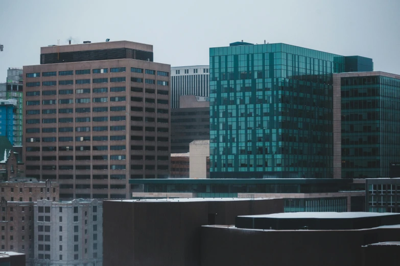 a couple of tall buildings sitting next to each other, by Andrew Domachowski, pexels contest winner, modernism, cold colors, southdale center, city below, slight overcast