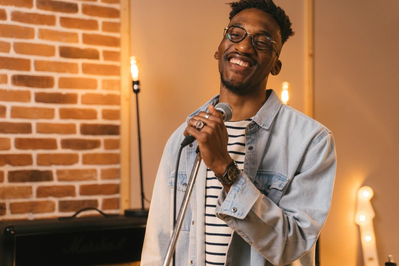 a man holding a microphone in front of a brick wall, by Amos Ferguson, trending on pexels, happening, mutahar laughing, ashteroth, studio picture, background image