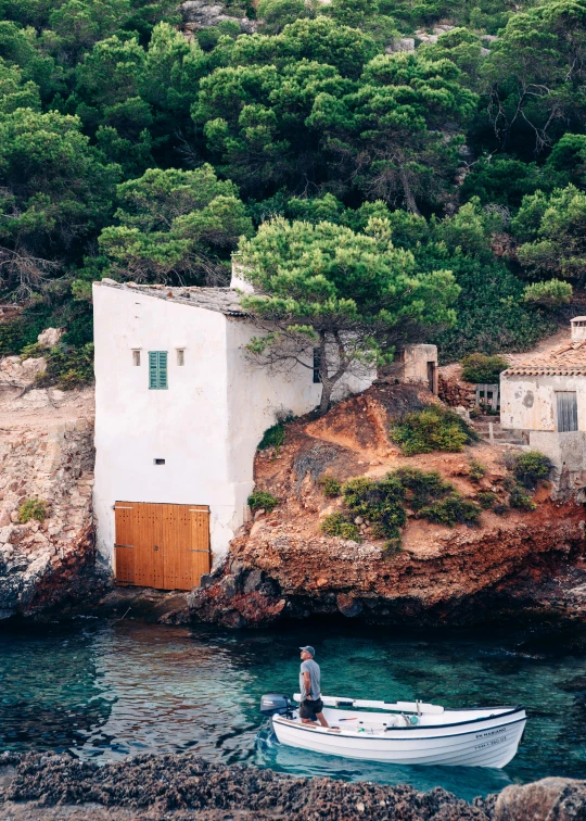 a small white boat sitting on top of a body of water, a picture, inspired by Antoni Pitxot, pexels contest winner, modernism, cozy bathhouse hidden in a cave, 2 5 6 x 2 5 6 pixels, in spain, conde nast traveler photo