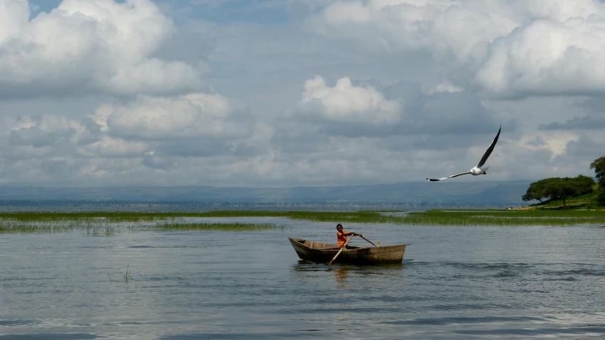 a couple of people in a small boat on a lake, by Peter Churcher, pexels contest winner, hurufiyya, birds flying in the distance, emmanuel shiru, slide show, thumbnail