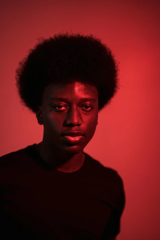 a man standing in front of a red light, pexels contest winner, black arts movement, portrait of 1 5 - year - old boy, afro hair, studio photo, black main color