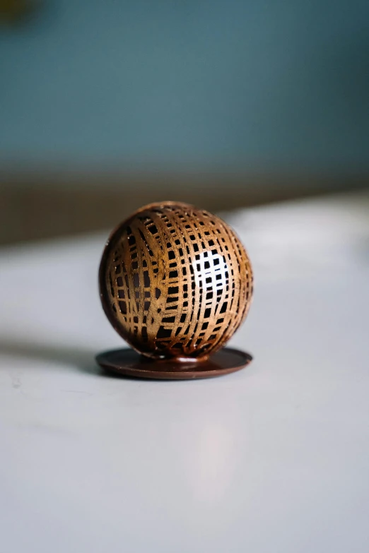 a wooden ball sitting on top of a table, by Thomas Furlong, unsplash, kinetic art, copper patina, laser cut textures, tabletop miniature, cloth and metal