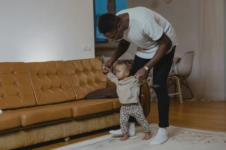 a man standing next to a little girl in a living room, pexels contest winner, happening, he is dancing, black people, brown clothes, 2 years old