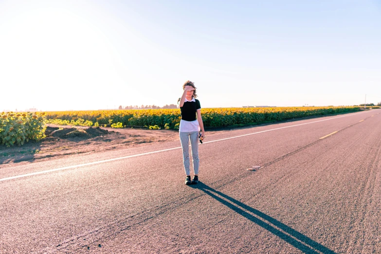 a woman riding a skateboard down the middle of a road, an album cover, by Anna Findlay, unsplash, happening, standing in a barren field, sydney hanson, wearing a crop top, central california