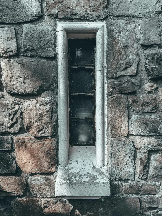 a window on the side of a stone building, inspired by Elsa Bleda, pexels contest winner, sewer pipe entrance, grey, gothic influence, cinder blocks