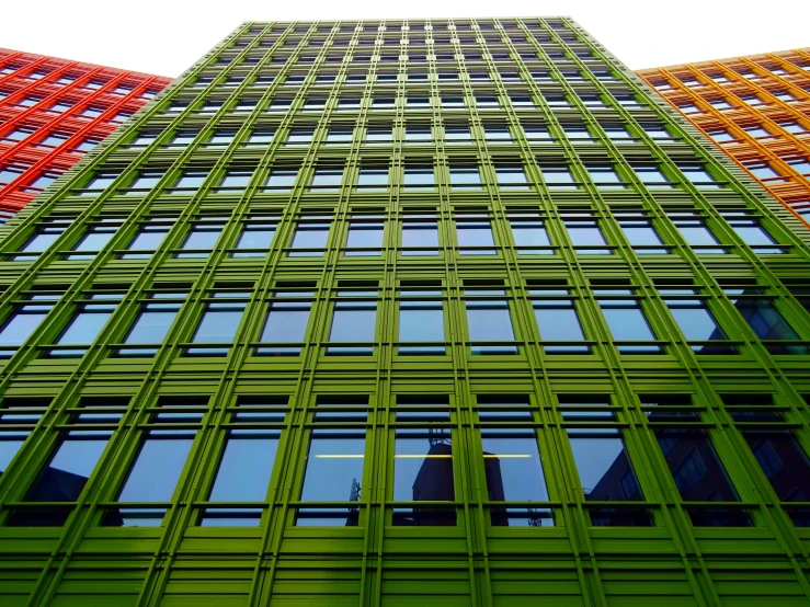 a very tall building with a lot of windows, flickr, vibrant green, laquer and steel, extremely colorful, ground level shot